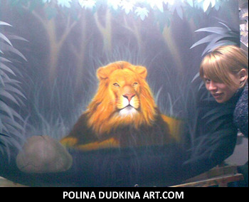 Polina with one of her airbrush paintings of a lion's head on a car hood